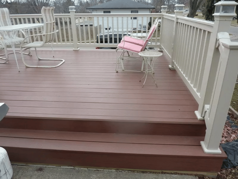 A brown deck surrounded by a white vinyl railing.