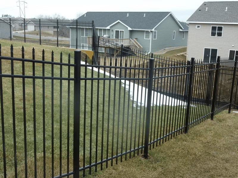 Black aluminum fencing along a sloped backyard.