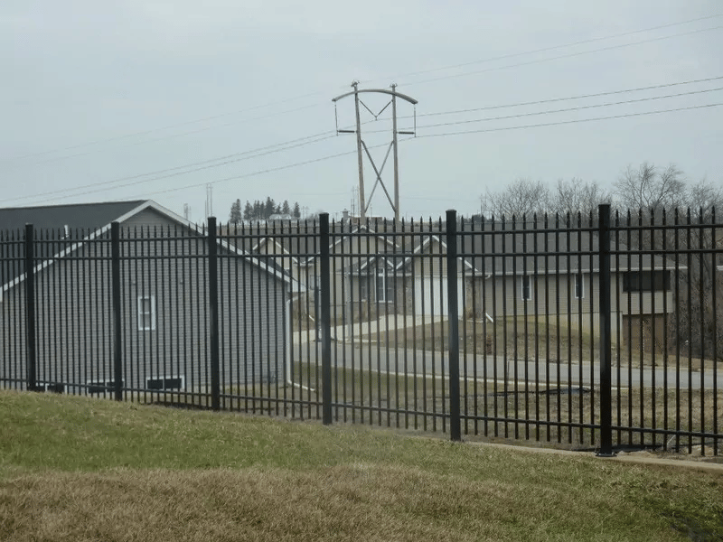 Black steel fence and gate beside a field.