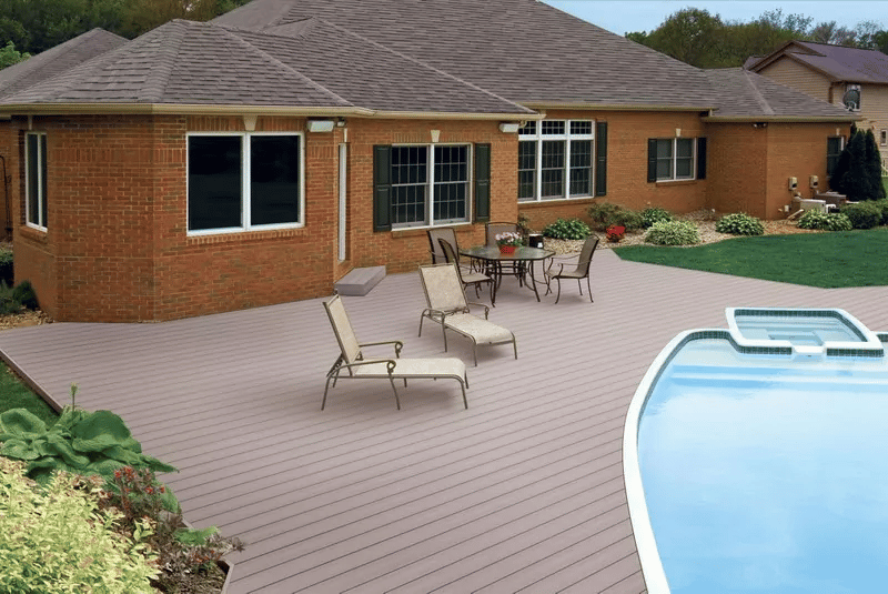 A pool deck behind a brick home.