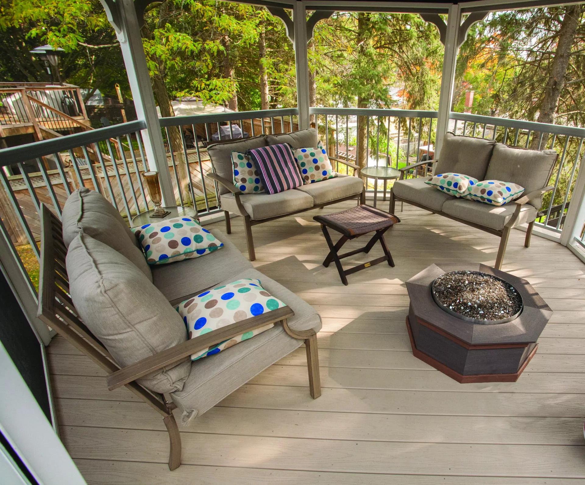 A custom deck with beige decking and railings, outdoor furniture, and a fire pit.