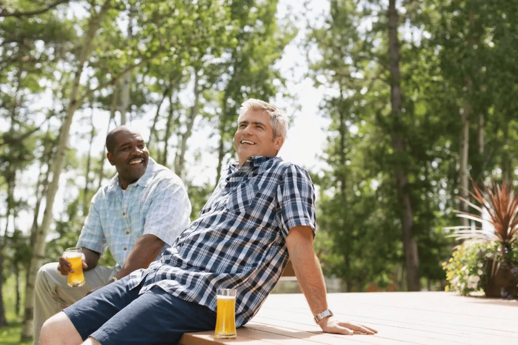Two men relaxing on a deck with drinks.