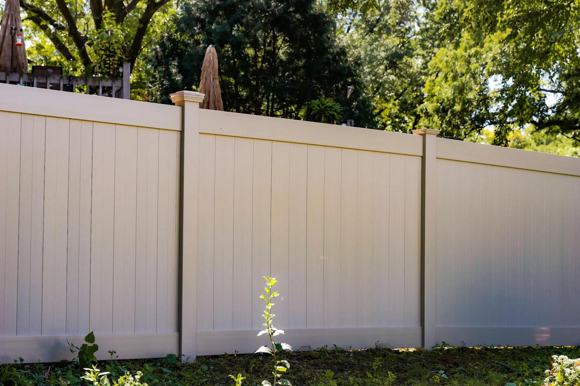 A tall vinyl privacy fence in a beige color.