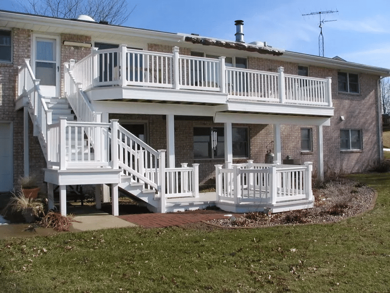 A two-level white deck on the back of a home.