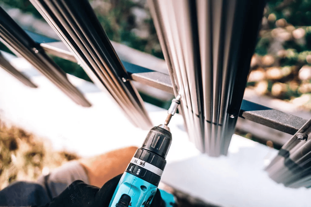 An installer fastening vinyl railing with a drill.