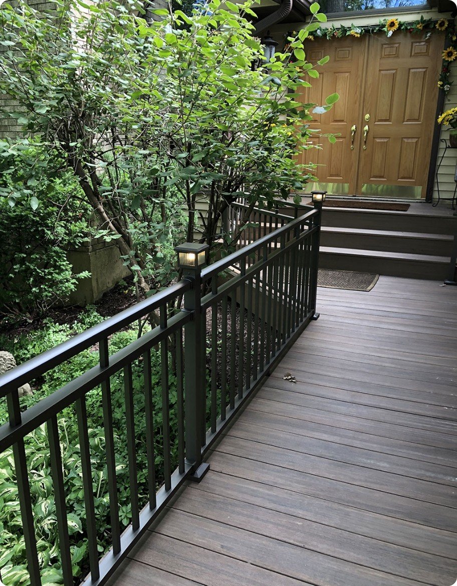 A dark porch with black aluminum railing and lit solar post caps.