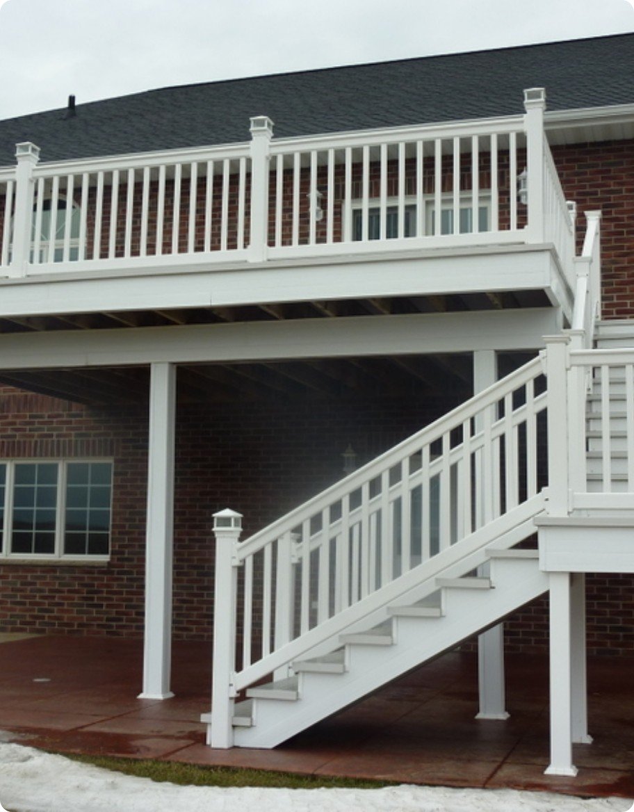 White vinyl stairs and balcony railings on a two story red brick home.