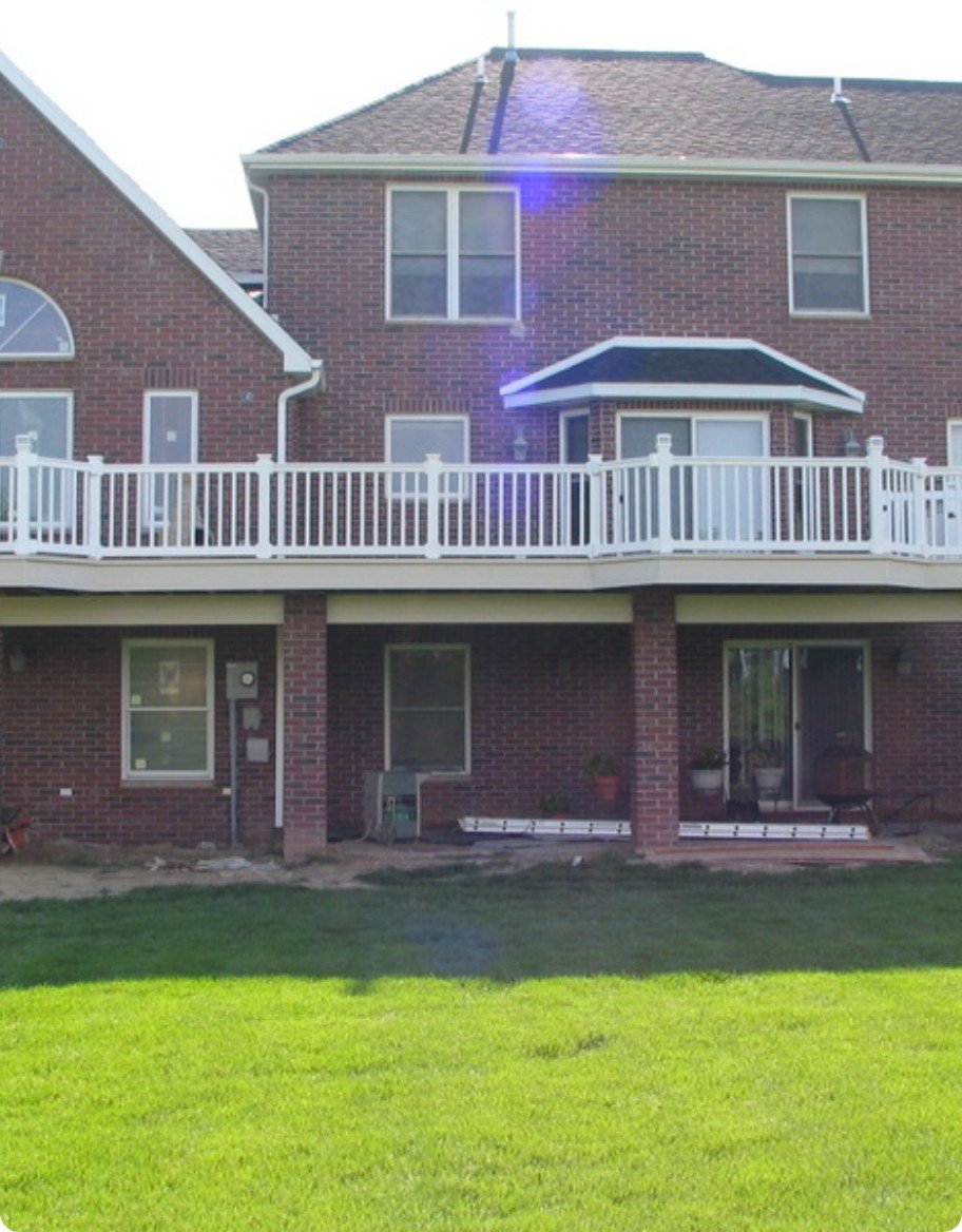 A red brick home with a white vinyl second floor balcony railing.