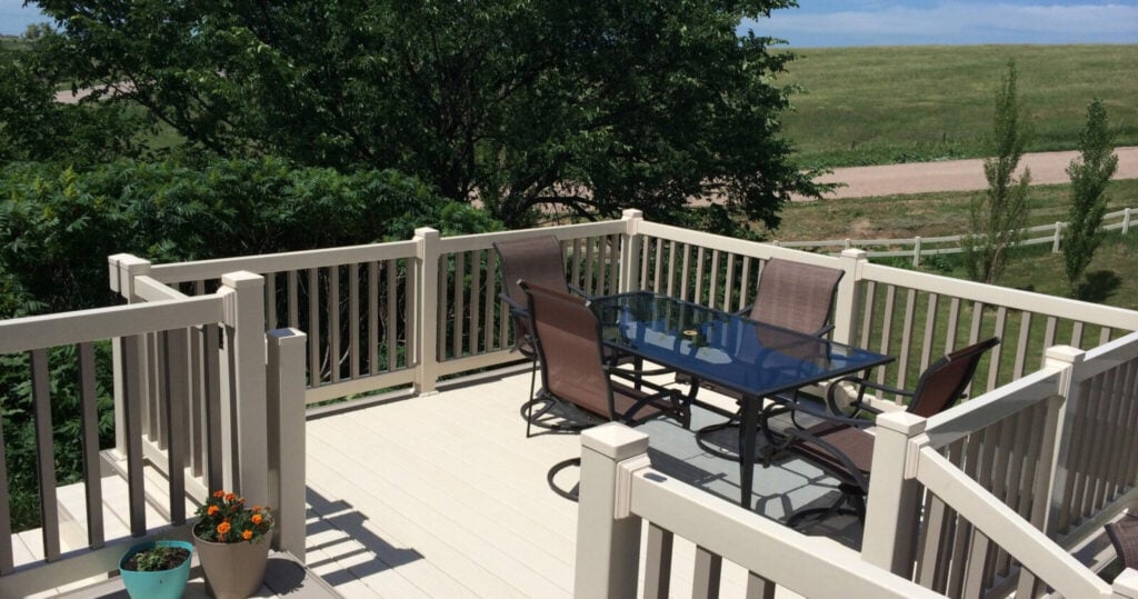 A beige deck with beige rails and tan vertical supports overlooking pasture.