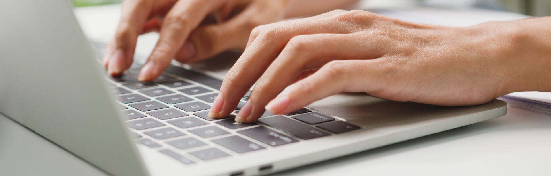 A woman's hands typing on a silver laptop