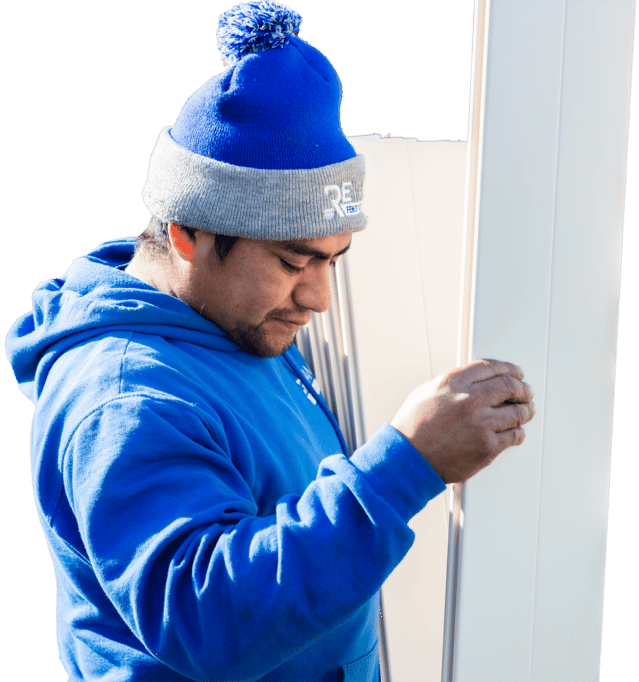 A ReVamp fence builder in a blue hoodie and beanie moving vinyl pieces.